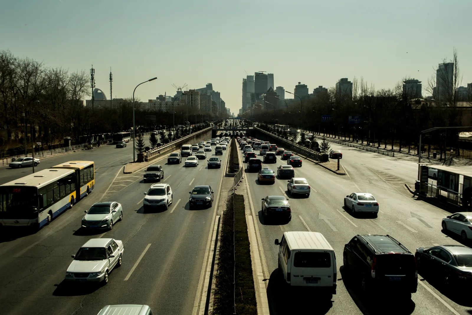 高處俯瞰分隔成兩向的多車道公路，車流通往遠方城市。