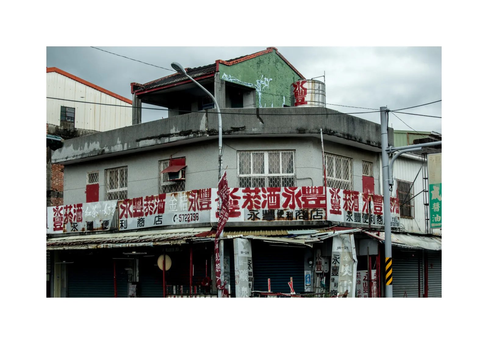 小冊子《1》第 28 頁：轉角建築的屋頂與外牆斑駁，店面上方排列紅色中文字招牌。