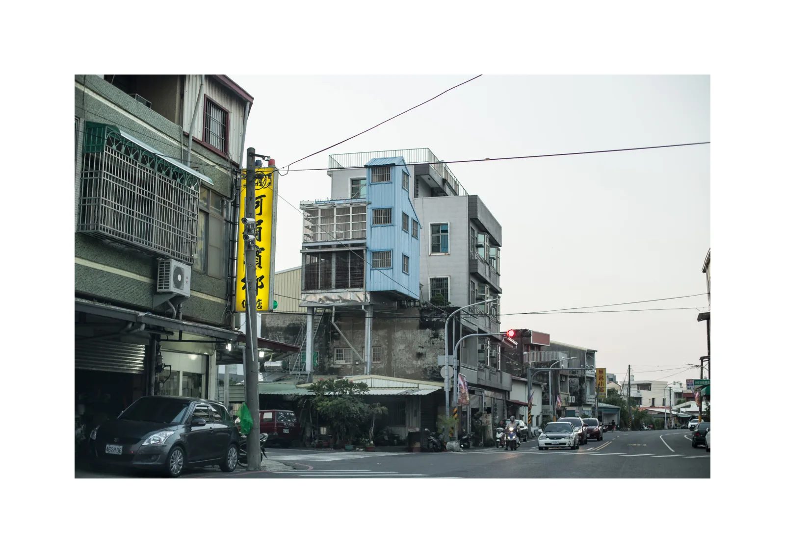 小冊子《B》第 2 頁：街道兩側的樓房、招牌與車輛，中間一棟樓房帶有大型格柵。