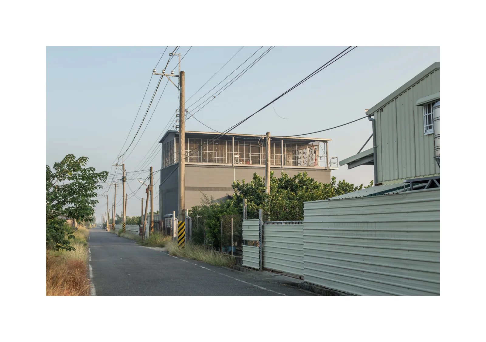 小冊子《B》第 25 頁：筆直小路沿著電線桿延伸，路旁是帶有格柵的建築與鐵皮圍籬。