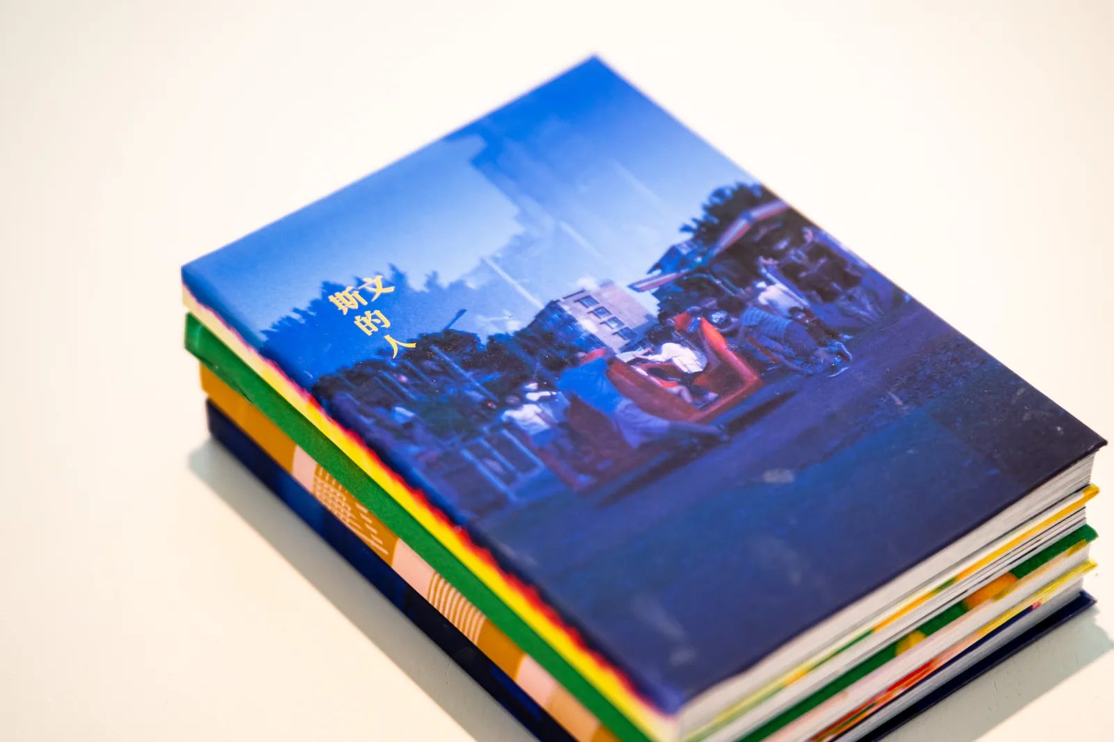 俯斜視角下，一疊手工書以藍色照片封面朝上放在白色展台。
