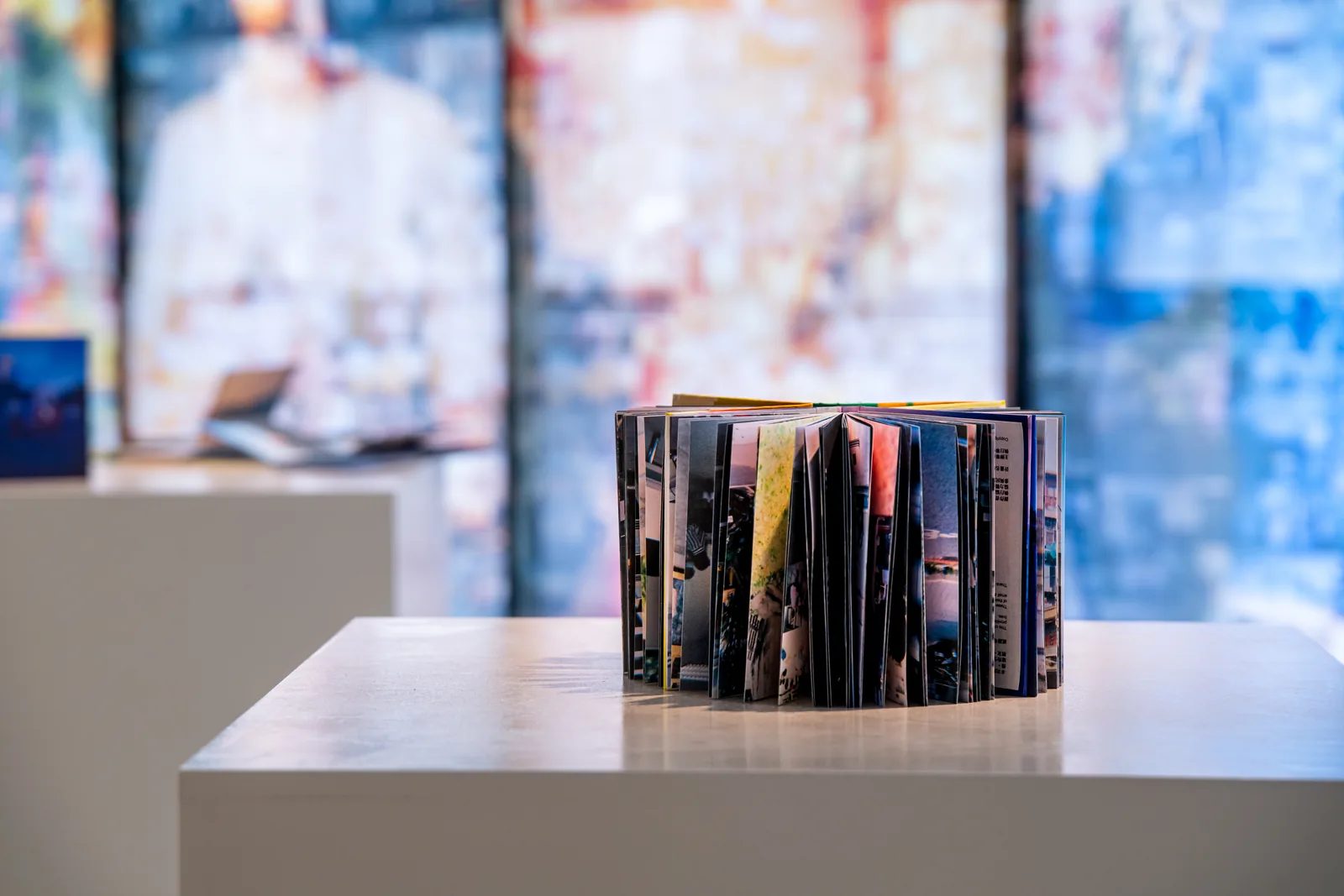 一本手工書直立展開成弧形，背景是彩色照片拼貼。